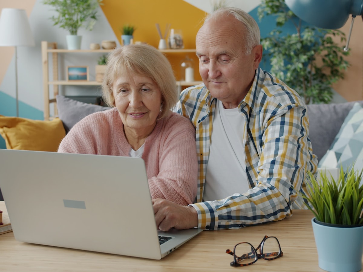 An older couple looking at a laptop screen together.
